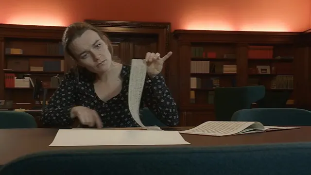 Eine Pianistin blättert in einem Archiv durch Notenhandschriften
